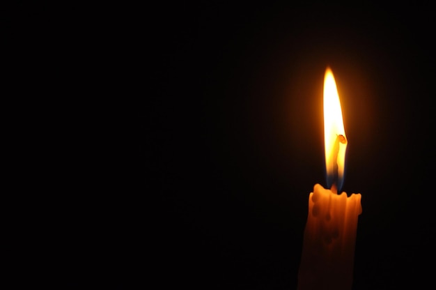 Close-up van een brandende kaars tegen een zwarte achtergrond