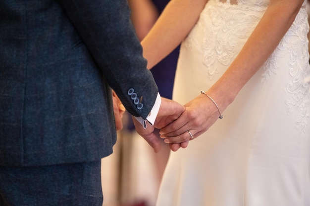 Close up van een bruid en bruidegom hand in hand tijdens huwelijksceremonie