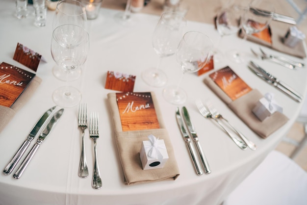 Close-up van een bruiloft eettafel bruine servetten met een ingesloten menu vorken en messen wijnglazen