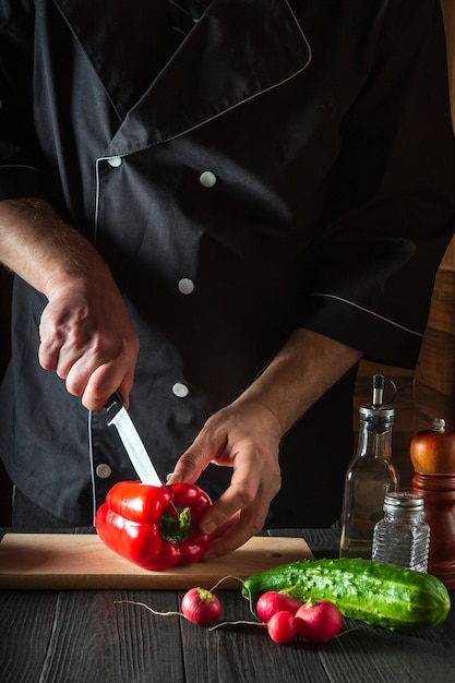 Close-up van een chef-kok die paprika's snijdt op een snijplank