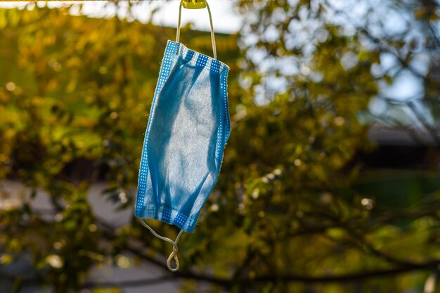 Foto close-up van een chirurgisch masker dat op een wasserand hangt met een natuurlijke achtergrond