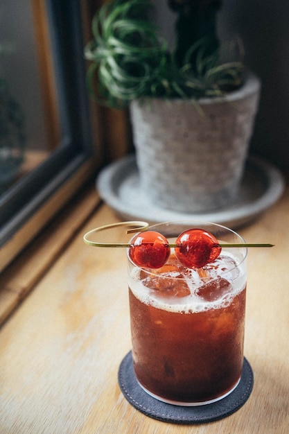 Close-up van een cocktail met kersen geserveerd op een houten tafel