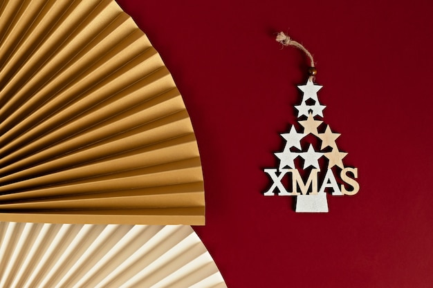 Foto close-up van een decoratieve kerstboom gemaakt van gouden sterren met een papieren ventilator. stijlvolle moderne kerstversiering op karmozijnrode muur