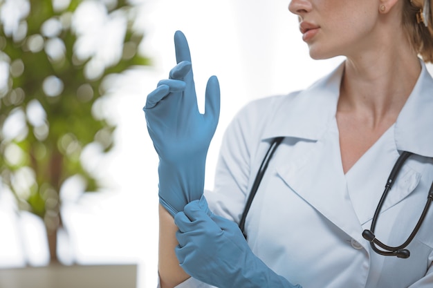 Close-up van een dokter op kantoor met een stethoscoop om zijn nek en een blauwe handschoen aan zijn hand