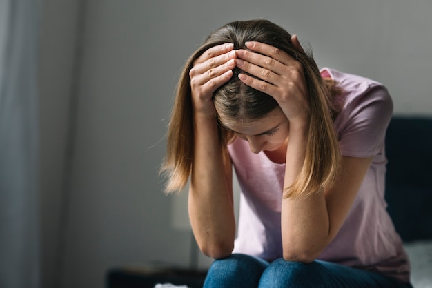 Foto close-up van een droevige jonge vrouw die haar hoofd houdt