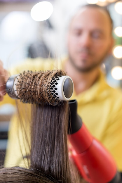 Close up van een drogend lang bruin haar met ronde borstel.