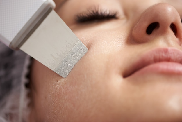 Close-up van een echografie gezichtspeeling uitgevoerd aan jonge vrouw met valse wimpers