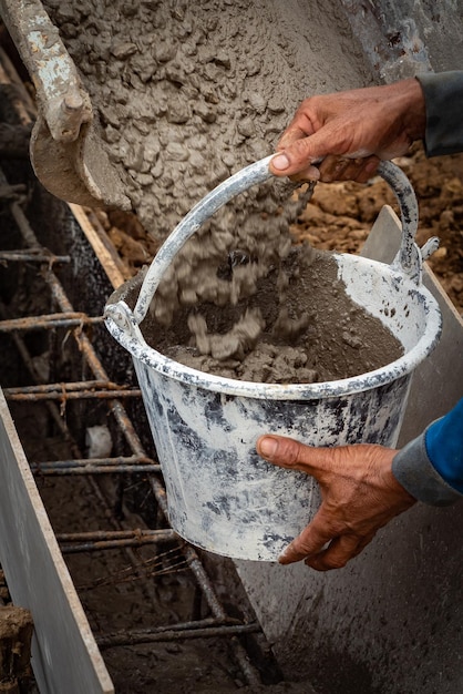 Close-up van een emmer die met de hand wordt gevuld met beton op een bouwplaats