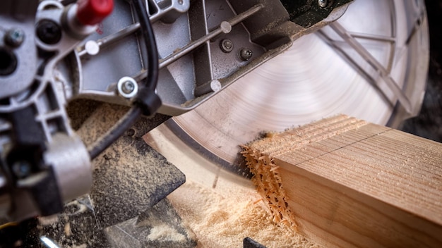 Close-up van een ervaren timmerman die een cirkelzaag gebruikt voor het zagen van houten planken