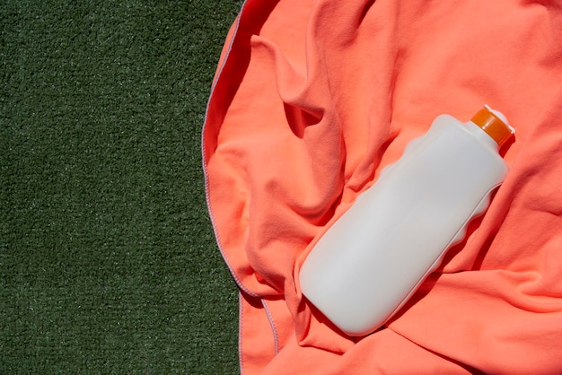 Foto close-up van een fles zonnebrandcrème op een oranje handdoek op gras