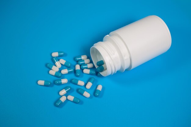 Close-up van een flesje met pillen met uitgestortte capsules
