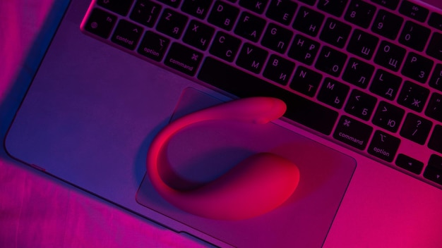 Close-up van een gebogen vibrator op een laptoptoetsenbord in blauwrood licht