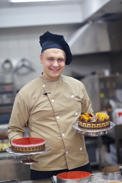 Foto close-up van een geconcentreerde mannelijke banketbakker die dessertcake in de keuken decoreert