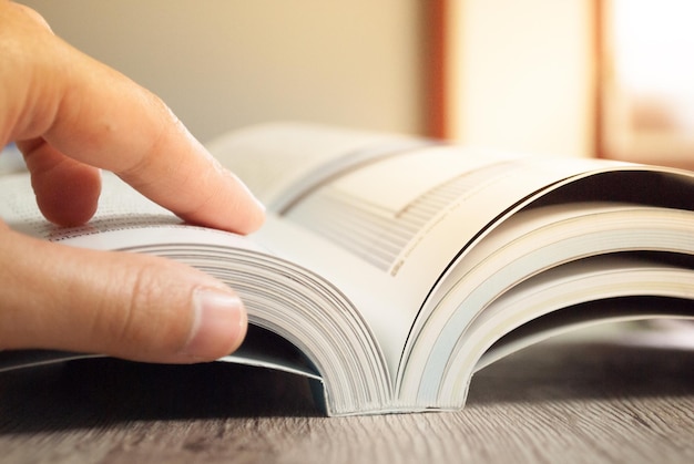 Foto close-up van een gekapte hand met een boek aan tafel