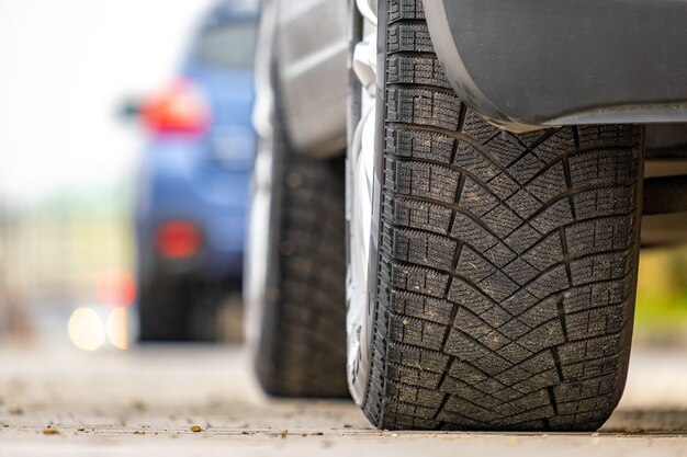 Close-up van een geparkeerde auto aan de straatkant van een stad met nieuwe rubberen winterbanden.