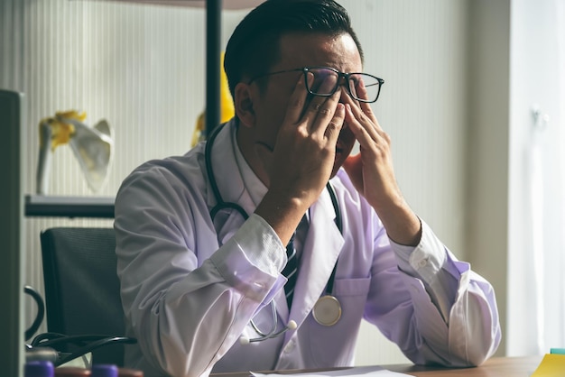 Foto close-up van een gestresseerde dokter die aan tafel zit