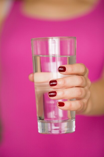 Close-up van een glas in de hand van een jong meisje met zoet water