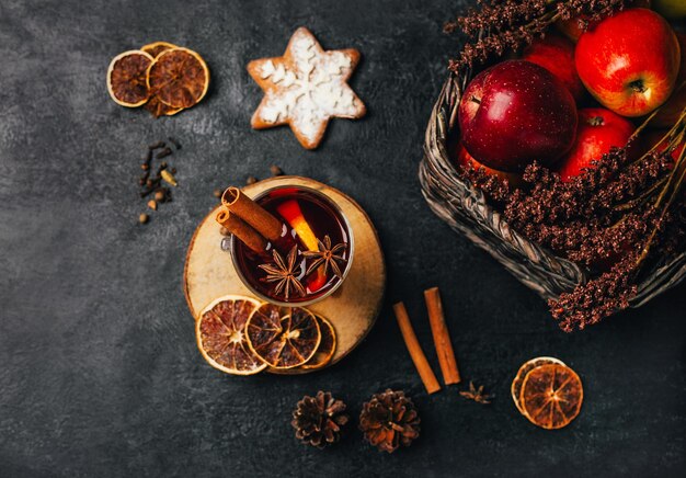 Foto close-up van een glas met gekookte wijn kaneel en kardemom op een zwarte achtergrond met ingrediënten voor de drank