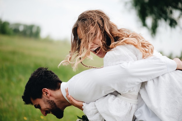 Close-up van een glimlachende man die een vrouw tegen de lucht draagt