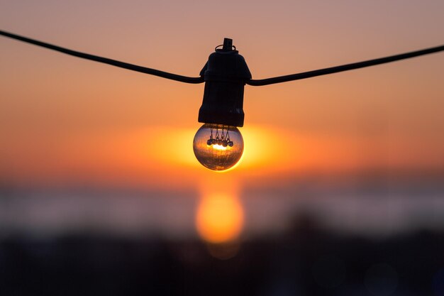 Foto close-up van een gloeilamp tegen de hemel bij zonsondergang