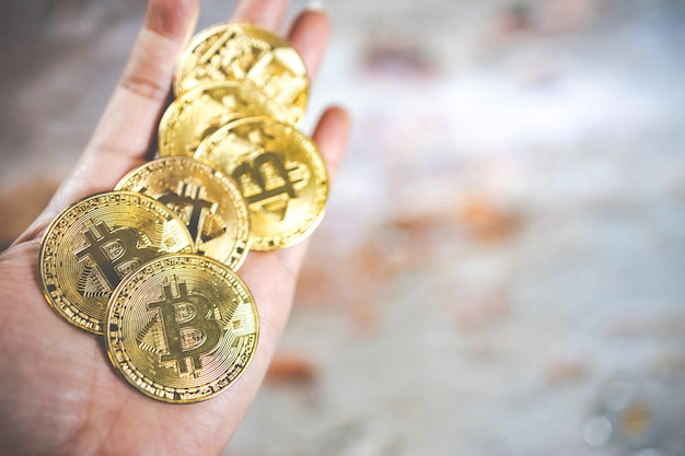 Close-up van een gouden munt met het bitcoin-symbool in de hand Jonge hand met cryptocurrency munt Geld munten digitale BTC