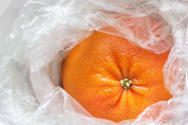 Close-up van een grapefruit gewikkeld in een witte plastic zak.
