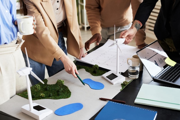 Close-up van een groep architecten die een nieuw milieuproject ontwikkelt met windmolens aan tafel