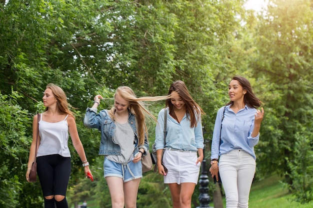 Close-up van een groep van vier vriendinnen die naar huis gaan na samen wandelen in het park. vrouwelijke studenten lopen na hun studie en hebben plezier