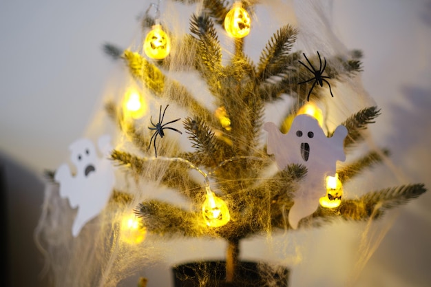 Close-up van een halloween-boom versierd met lichtspinnenwebben en decoratieve geesten