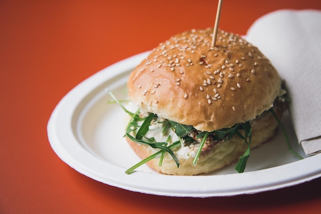 Close-up van een hamburger die op een rode tafel wordt geserveerd