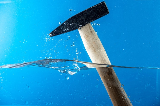 Close-up van een hamer in het water tegen een blauwe achtergrond