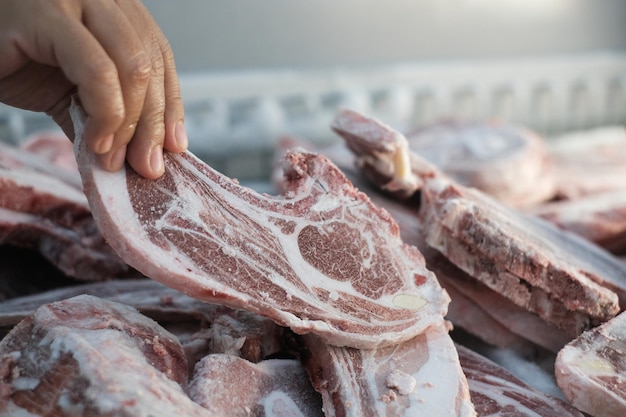 Close-up van een hand die bevroren vlees vasthoudt op de markt
