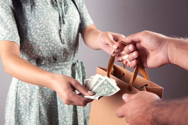 close-up van een hand die boodschappentassen vasthoudt en contant geld dollars betaalt