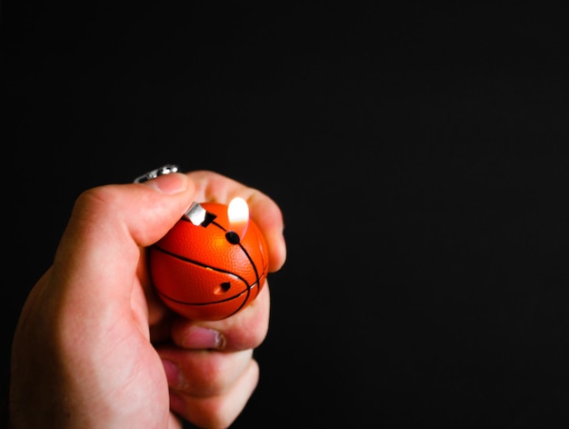 Foto close-up van een hand die een aansteker aansteekt op een zwarte achtergrond