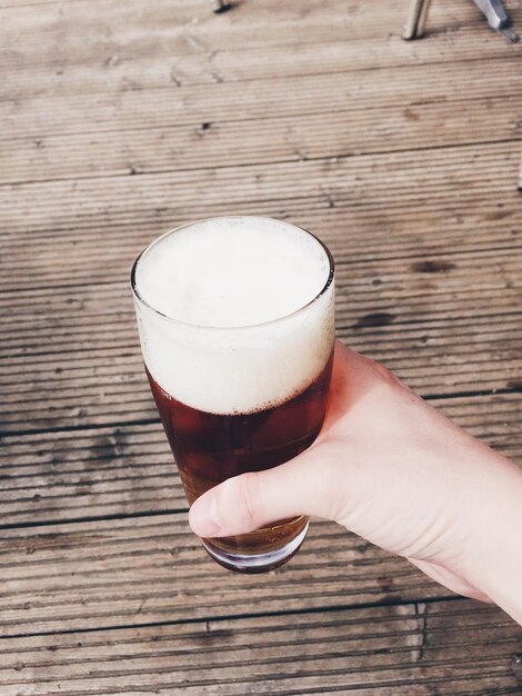 Foto close-up van een hand die een bierglas op tafel houdt