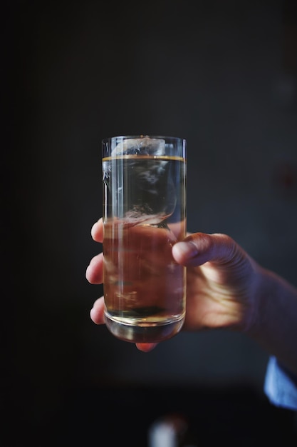 Close-up van een hand die een drankje vasthoudt op een zwarte achtergrond
