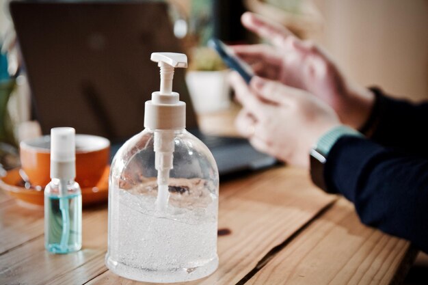 Close-up van een hand die een glazen fles op tafel houdt