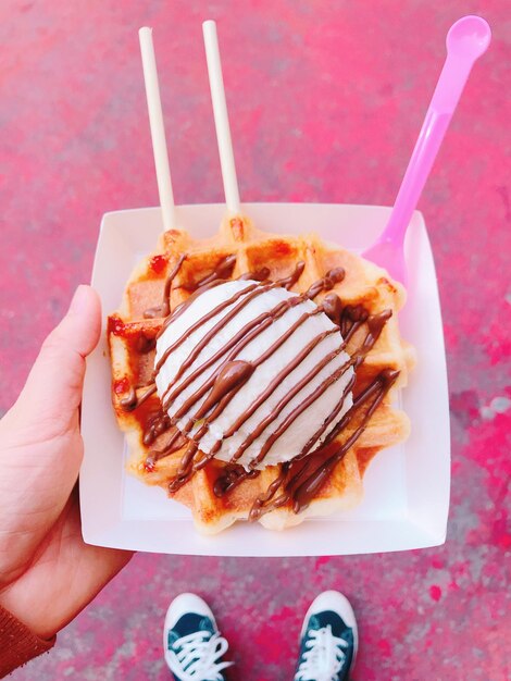 Close-up van een hand die een ijsje vasthoudt met een wafel op een bord