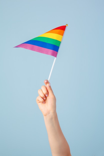 Close-up van een hand die een kleine regenboogvlag zwaait