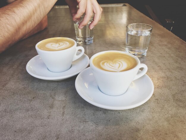 Close-up van een hand die een koffiekop op tafel houdt