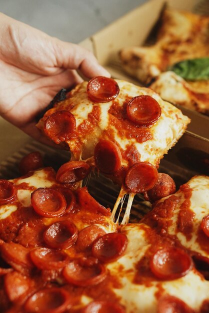 Foto close-up van een hand die een pizza vasthoudt