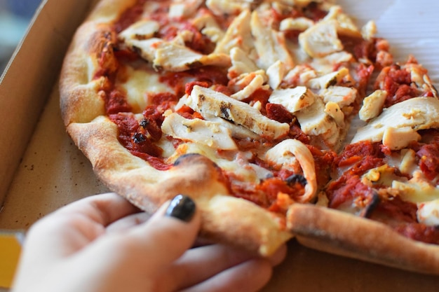 Foto close-up van een hand die een pizza vasthoudt