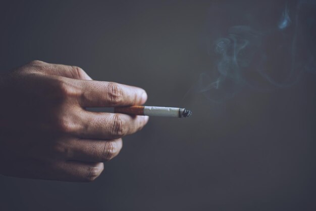 Close-up van een hand die een sigaret vasthoudt tegen een grijze achtergrond