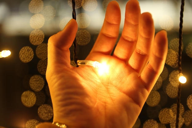 Foto close-up van een hand die een verlichte snaarlamp vasthoudt