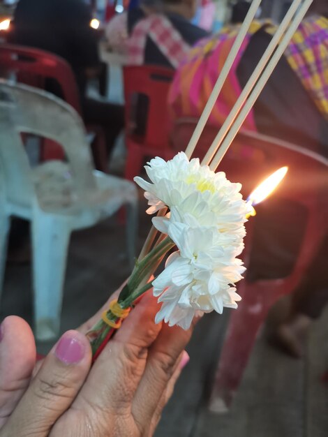 Foto close-up van een hand die een wierookstok met een bloem vasthoudt