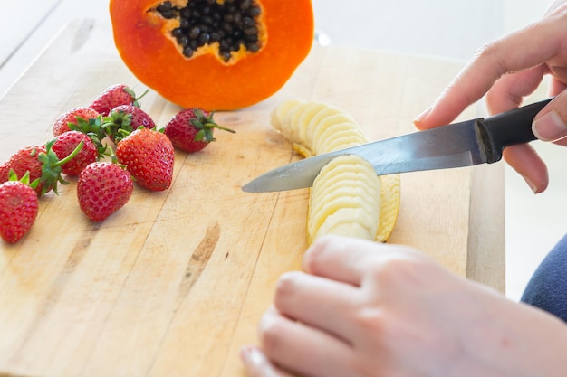 Close-up van een hand die fruit op een snijplank houdt