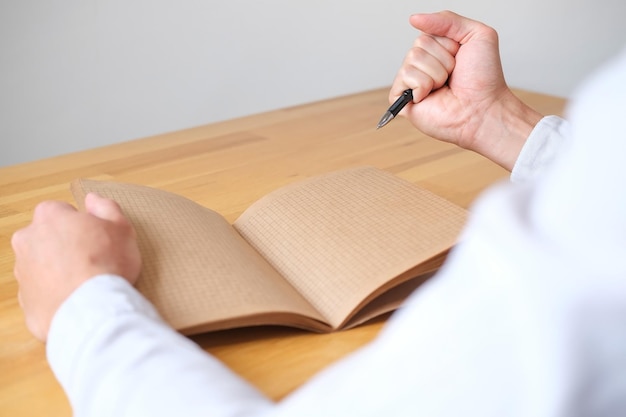 Close-up van een hand met een vuist met pen tegen de achtergrond van een notitieboekje