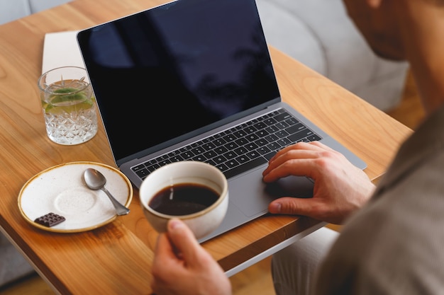 Close-up van een heer die koffie drinkt en werkt aan een modern notitieboekje in café