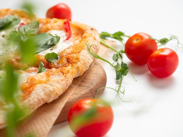 Close-up van een heerlijke Romeinse pizza met groenten op een witte achtergrond rijpe rode tomaten en microgreens liggen in de buurt Traditioneel Italiaans eten Zijaanzicht selectieve aandacht