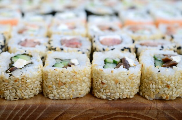 Close-up van een heleboel sushi rollen met verschillende vullingen liggen op een houten oppervlak. Macro-opname van gekookte klassieke Japanse gerechten